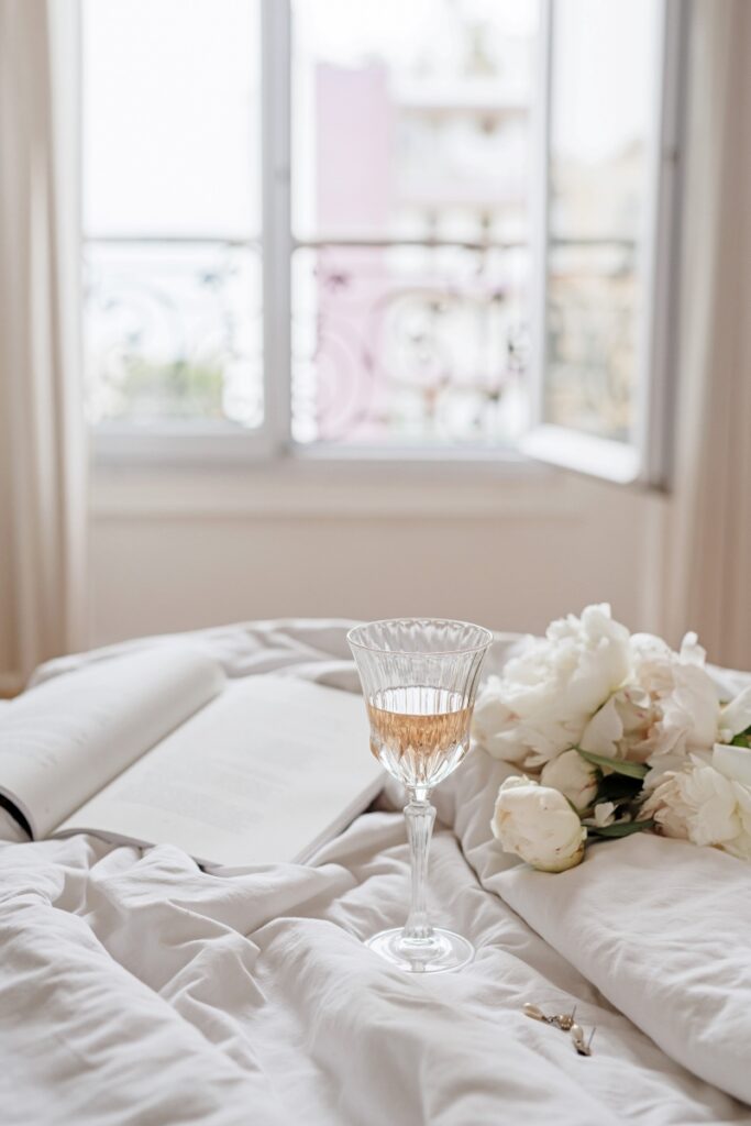 Serene bed with a tray holding champagne, flowers, and a journal—an invitation to slow down and create joy.