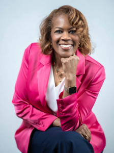A smiling woman with warm, welcoming eyes sitting on a bench.