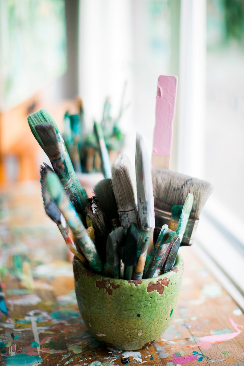 Assorted used paint brushes in a glass jar representing artistic outlets and creative outlet ideas for stress relief and self-expression.