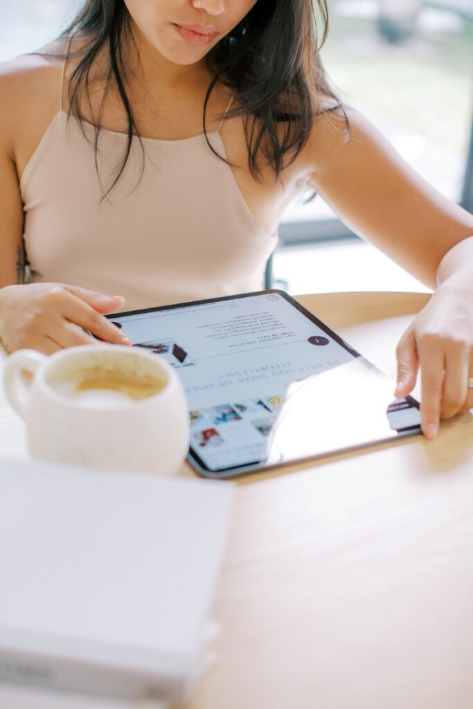 Woman seated with coffee, reading blogs Christian women love on her iPad at the table.