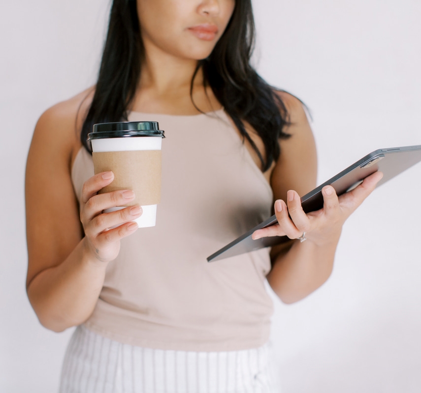Woman holding an iPad and cup of coffee while reading blogs Christian women love for faith and encouragement.