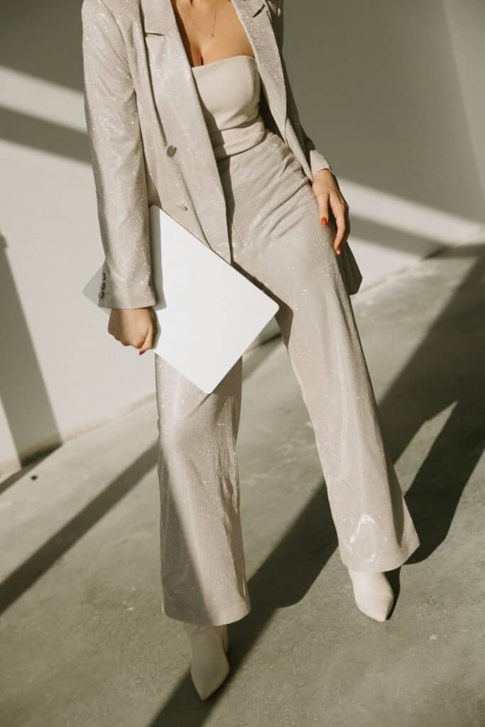 Midlife woman wearing a sleek taupe suit, standing confidently and smiling, showcasing the comfort and fit that body-positive dress brands and inclusive clothing can offer.