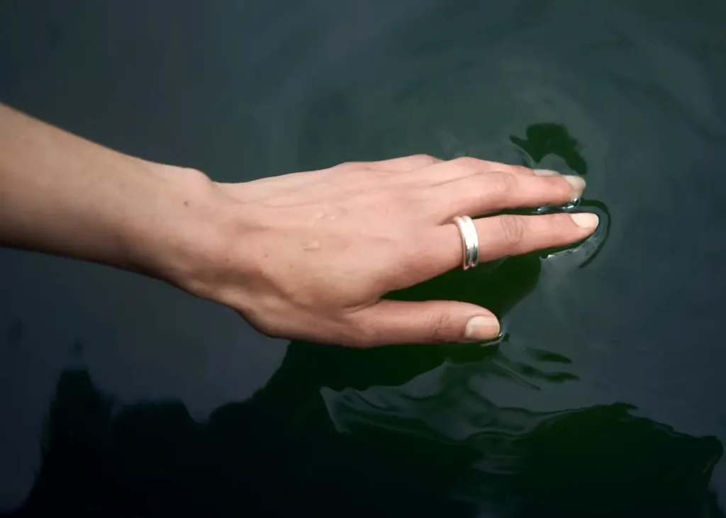 Hand gently touching calm water — a soothing, grounding visual representing how to reset your nervous system in midlife.