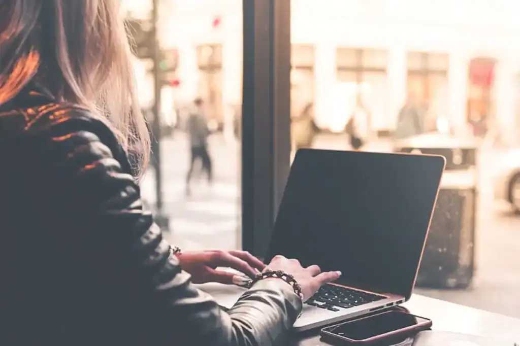 Midlife woman sitting at a laptop, exploring new possibilities during a career change at 50.