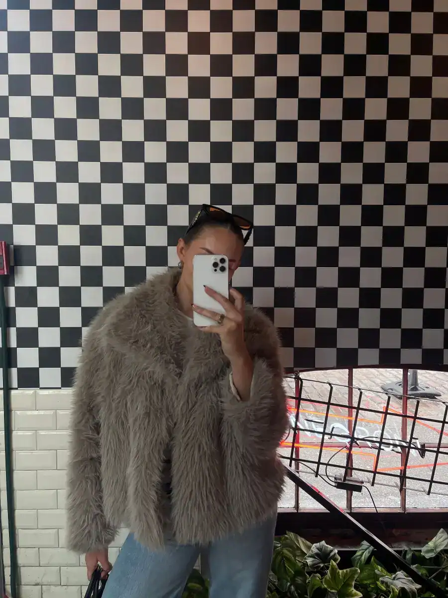 A woman in a fur coat, choosing bold pieces after deciding she doesn't want a capsule wardrobe anymore